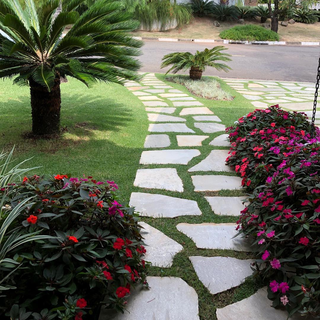 Caminho de pedras irregulares com grama e flores coloridas