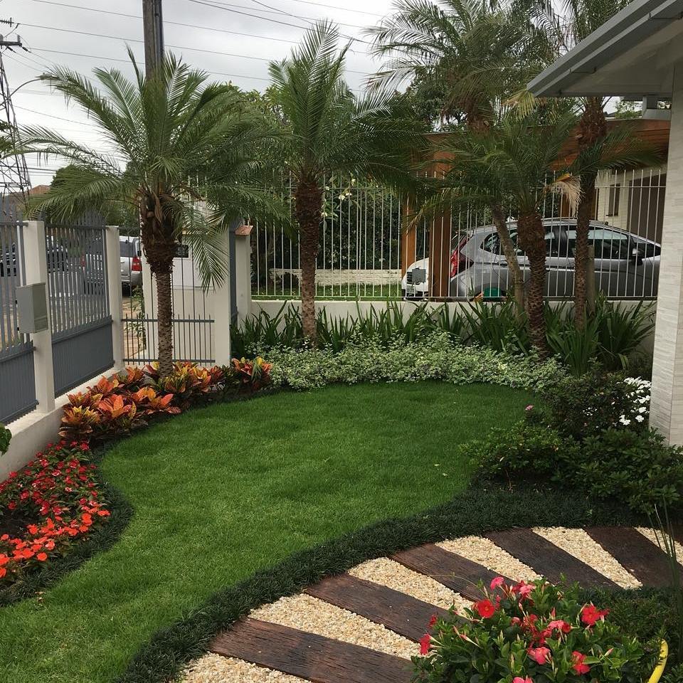 Jardim frontal com palmeiras e caminho de dormentes